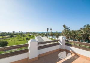 a balcony with a view of a road and palm trees at PUSHE Village Playa Granada Beach & Golf 3 in Motril