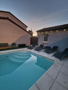 uma piscina com cadeiras sentadas ao lado de um edifício em Maison individuelle avec sa piscine privée em Clermont-Ferrand