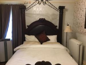 a bedroom with a large bed with a wooden headboard at Marmora and Lake Inn and Victorian Diner in Marmora