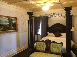 a bedroom with a canopy bed with a chair at Marmora and Lake Inn and Victorian Diner in Marmora