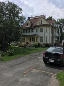 a black car parked in front of a large house at Marmora and Lake Inn and Victorian Diner in Marmora