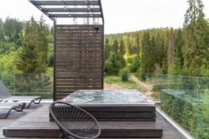 bañera de hidromasaje en una terraza con vistas al bosque en Bukville Hotel & SPA en Bukovel