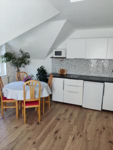 a kitchen with white cabinets and a table and chairs at FaDóra Apartman in Tihany