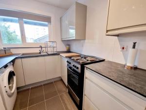 a kitchen with a stove top oven next to a dishwasher at One Bed Holiday Home in the Heart of Glasgow in Glasgow