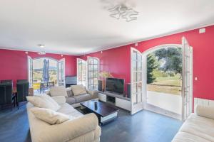 uma sala de estar com paredes vermelhas e mobiliário branco em CABANA & La Villa sur la Colline - Au Calme 