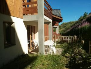 een patio met een tafel en stoelen op een huis bij Appartement calme au pied des pistes in Valmeinier