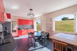 a kitchen with red cabinets and a table and chairs at CABANA & La Villa sur la Colline - Au Calme 