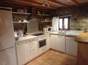 a kitchen with white appliances and a stone wall at Amplia y cómoda casa de piedra con porche y jardín in San Roque de Ríomiera