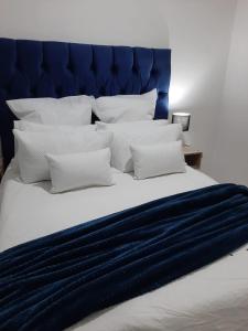 a large bed with a blue headboard and white pillows at The Cottage II in Grahamstown