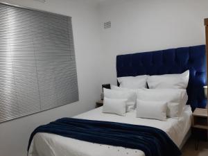 a bed with a blue headboard and white pillows at The Cottage II in Grahamstown