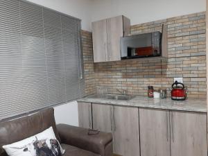 a kitchen with a couch and a sink and a microwave at The Cottage II in Grahamstown