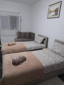 three beds in a room with a couch at Apartmani Pejovic in Mojkovac