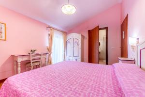 een roze slaapkamer met een groot bed en een bureau bij B&B Capriccio in Rocca Priora