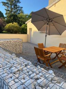 uma mesa de madeira e duas cadeiras com um guarda-sol em Maison rénovée au calme em Dannevoux