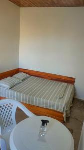 um pequeno quarto com uma cama, uma mesa e uma cama branca em Suítes Pé Nareia Itaipuaçu em Maricá