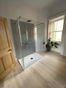 um chuveiro de vidro num quarto com piso de madeira em Purves Cottage em Allanton