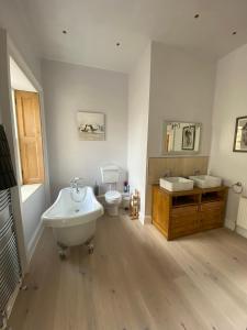 uma casa de banho com 2 lavatórios, uma banheira e um WC. em Purves Cottage em Allanton
