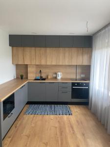 a kitchen with wooden cabinets and a wooden floor at Feelings Apartment apartamenti Smiltene in Smiltene