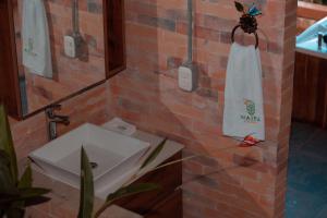 Waira Eco Lodge في فيلافيسينسيو: حمام مع حوض ومنشفة على جدار من الطوب