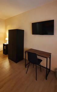 una scrivania con sedia e una TV appesa a un muro di Pacifico Rooms a San Bartolomeo in Galdo