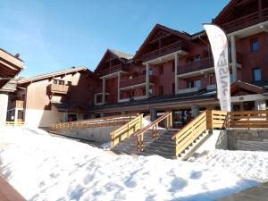 un edificio con escaleras y un cartel en la nieve en Appartement calme au pied des pistes en Valmeinier