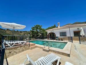 a swimming pool with two chairs and a house at FINCA EL ALMENDRO in Málaga
