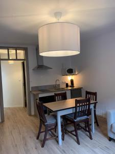 cocina con mesa, sillas y lámpara en Gîte du clocher dans ancienne maison du vignoble en Niedermorschwihr
