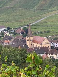 una pequeña ciudad con una iglesia en un campo en Gîte du clocher dans ancienne maison du vignoble en Niedermorschwihr