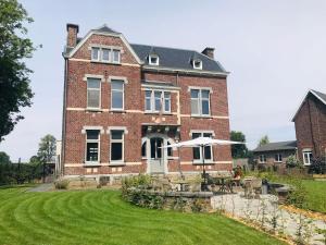 a large red brick house with a lawn in front of it at B&B het Notarishuis in Voeren