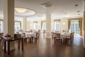 a dining room with tables and chairs and windows at Dworek nad Rozlewiskiem in Olkusz