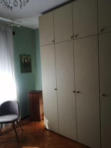 um quarto com armários brancos, uma cadeira e uma janela em Villa Signorina em San Francesco al Campo