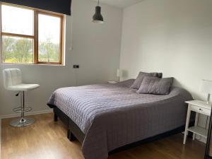a bedroom with a bed and a chair and a window at Halakot guesthouse in Laugardælir