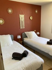 Dos camas en una habitación de hotel con toallas negras. en Gite Le Canigou 3* dans un Mas typique catalan en Prades