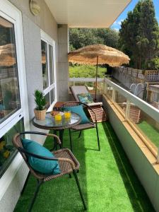 - un balcon avec une table, des chaises et un parasol dans l'établissement Samil primera línea de playa, à Vigo