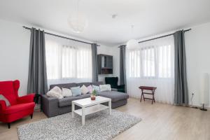 ein Wohnzimmer mit einem Sofa und einem roten Stuhl in der Unterkunft Zola Guest House in Oradea
