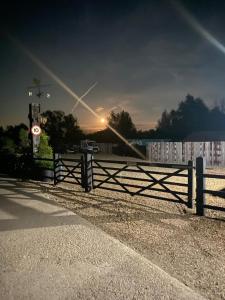 a fence in front of a building with the sunset in the background at Lake View Lodges in Long Melford