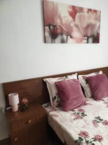 1 cama con almohadas rosas y una foto en la pared en Sun & Sea 3 Bedroom Apartment de Grau, en Gandía