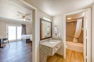 a bathroom with a sink and a tub and a bedroom at Harbor House Inn in Morro Bay