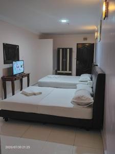 Zimmer mit 3 Betten und einem Laptop auf einem Tisch in der Unterkunft TAMIM SUITE GROUP HOTEL Dungun in Dungun