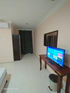 a living room with a tv and a desk with a computer at TAMIM SUITE GROUP HOTEL Dungun in Dungun