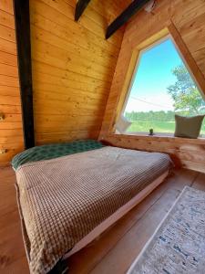 Bett in einem Blockhaus mit Fenster in der Unterkunft Blackcherry_Ukraine in Chereshenka