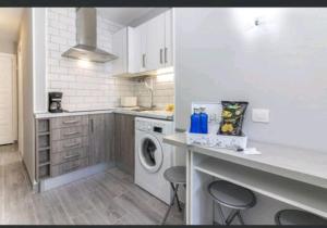 uma cozinha branca com uma máquina de lavar roupa e cadeiras em Apartamento en Paraíso San Telmo em Puerto de la Cruz