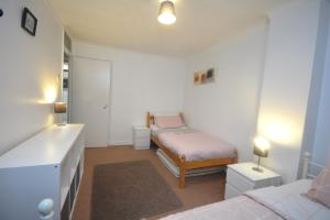 a small bedroom with a bed and a dresser in it at Spacious 3 bedroom House in Tilbury by London in Low Street