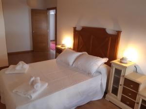 a bedroom with a large white bed with towels on it at Apartamento Reguiño al mar in A Guarda