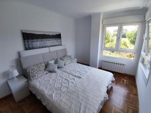 1 dormitorio con 1 cama blanca y 2 ventanas en Apartamento MAR y MONTAÑA ASTURIAS, en Posada de Llanes