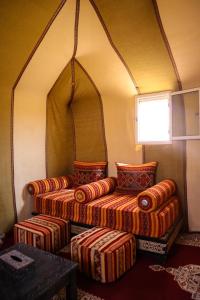 a room with two beds and a table and a window at Merzouga Paradise Luxury Camp in Merzouga