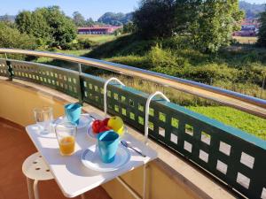 una mesa con 2 vasos de zumo de naranja y fruta en el balcón en Apartamento MAR y MONTAÑA ASTURIAS, en Posada de Llanes