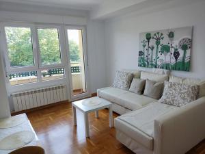 a living room with a white couch and two windows at Apartamento MAR y MONTAÑA ASTURIAS in Posada de Llanes