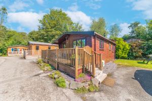 a log cabin with a porch and a fence at Bowness 45 - 2 bedroom Lake Windermere Lodge in Windermere