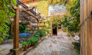 a garden with a pergola and a table and plants at Casa Rural La Yedra in Galve